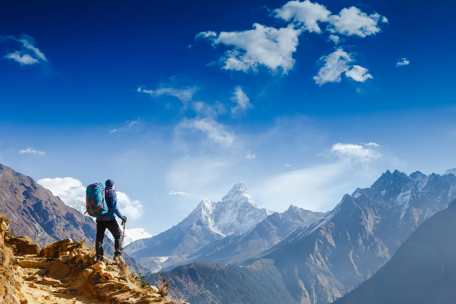 A walker on a mountain ridge looking out at snow-capped peaks